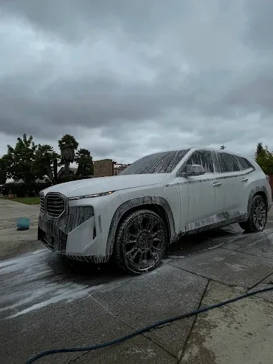 White BMW XM covered in thick foam during a mobile hand wash